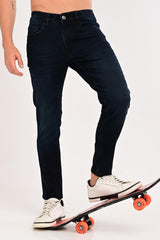 Tapered ankle fit of IVYN Midnight Indigo Wash jeans styled with sneakers and a skateboard