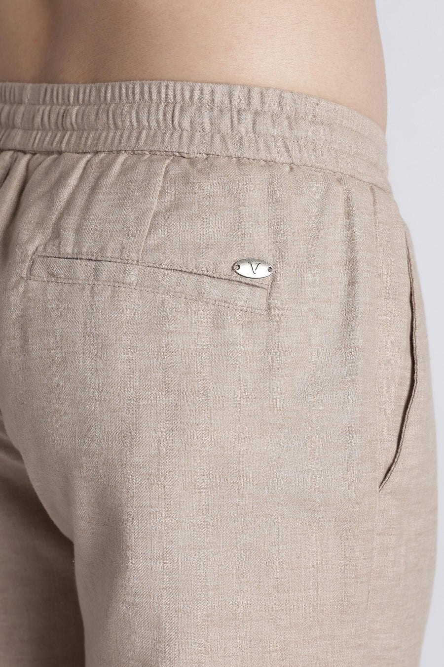Back pocket and IVYN metal badge detail on mushroom taupe trousers