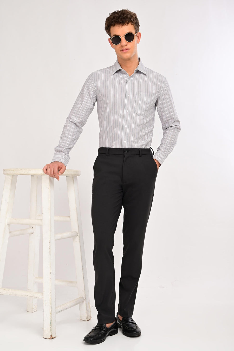 Model wearing IVYN Regent Charcoal slim-fit formal trousers with a striped shirt