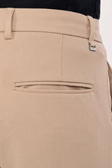 Rear welt pocket and IVYN metal badge detail on mink beige tailored trousers